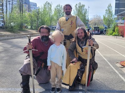 Pose de membres de la Compagnie en costume médiévaux aux cotés d'un enfant